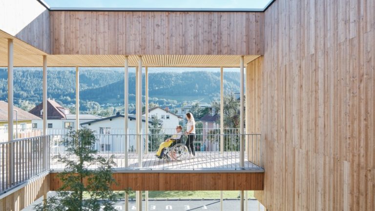 Der Balkon des Hospizhauses. Eine Frau schiebt einen Patienten im Rollstuhl.