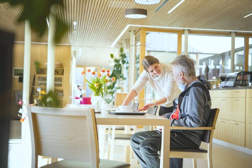 Schwester mit Patient am Esstisch auf der Station