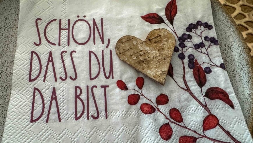 Eine Serviette mit der Aufschrift "Schön das du da bist" mit Herz und gezeichneten roten Blättern