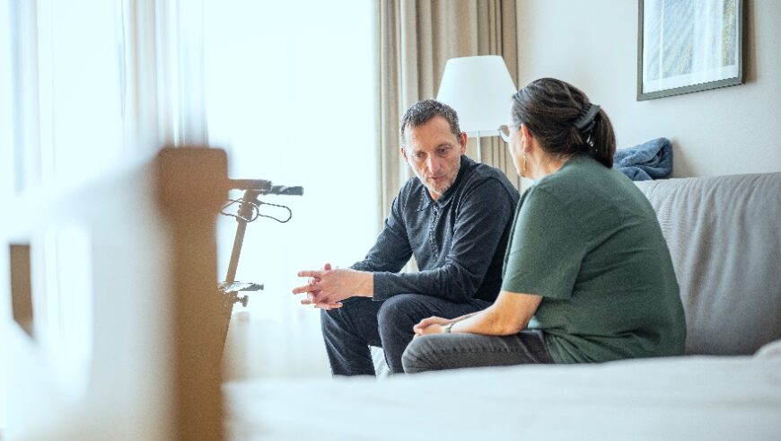 Ein Patient mit einer Krankenpflegerin im Gespräch auf der Station im Hospizhaus