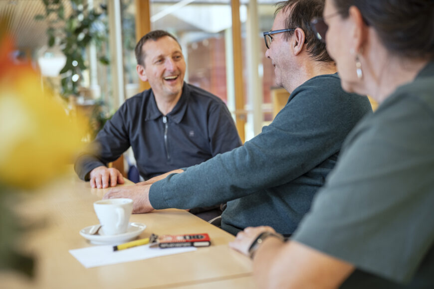 Lachende Patienten am Gemeinschaftstisch im Tageshospiz